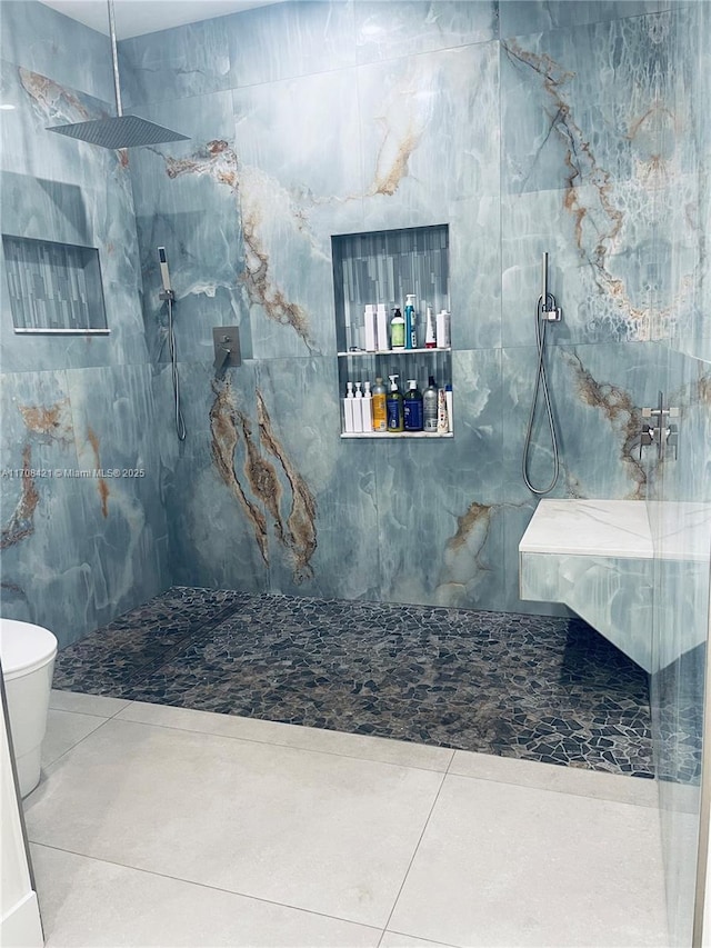 bathroom featuring toilet, a marble finish shower, and tile patterned floors