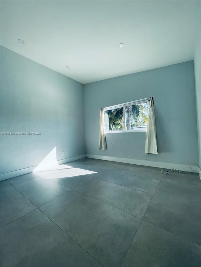 spare room featuring concrete flooring and baseboards