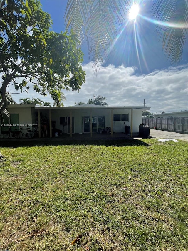 rear view of property with fence and a yard