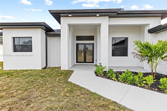 doorway to property featuring french doors and a lawn