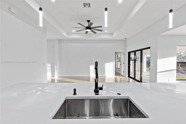 kitchen featuring a raised ceiling, sink, and hanging light fixtures