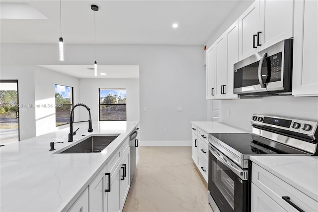 kitchen with light stone countertops, appliances with stainless steel finishes, white cabinetry, and sink