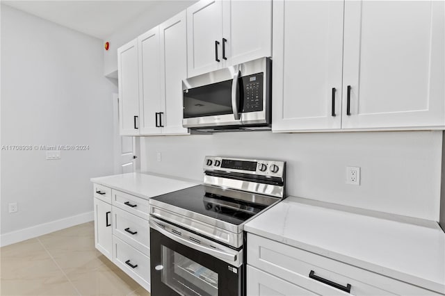 kitchen with light stone countertops, appliances with stainless steel finishes, and white cabinetry