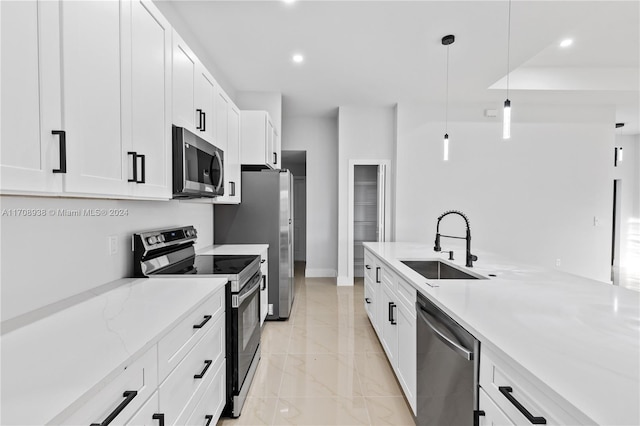 kitchen featuring white cabinets, sink, hanging light fixtures, light stone countertops, and stainless steel appliances