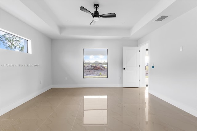 spare room with a tray ceiling and ceiling fan