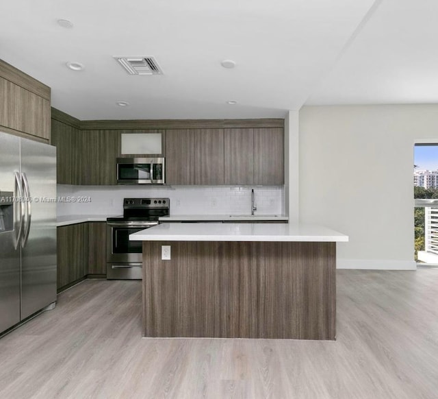 kitchen with light hardwood / wood-style flooring, a center island, stainless steel appliances, and sink