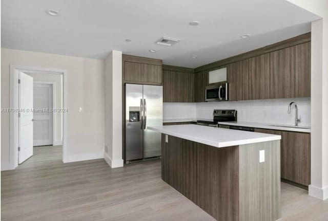 kitchen with a center island, a kitchen breakfast bar, sink, light wood-type flooring, and stainless steel appliances