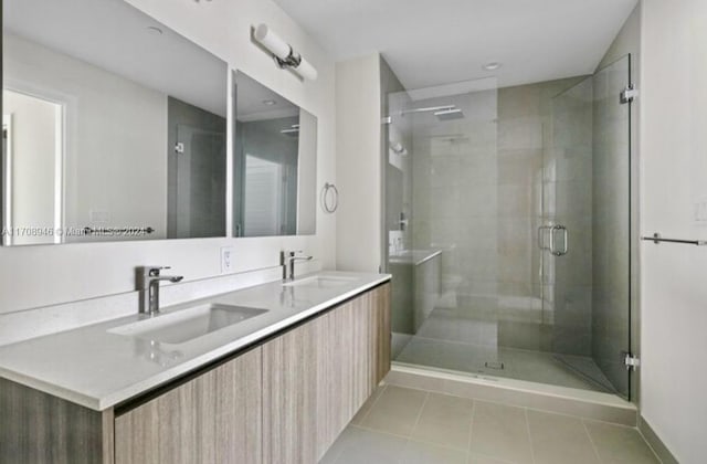 bathroom with a shower with door, vanity, and tile patterned flooring