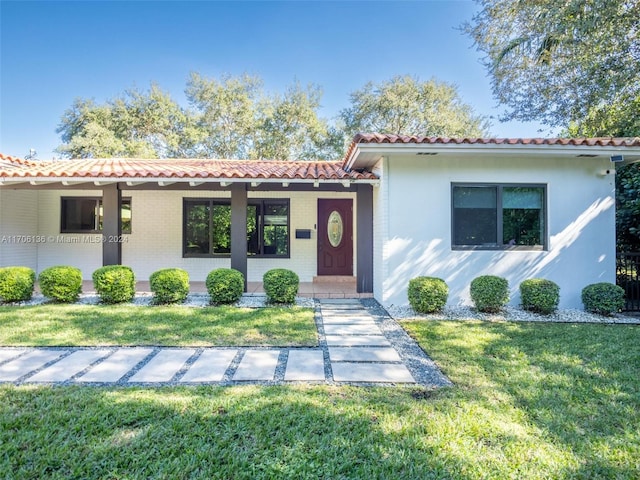 mediterranean / spanish-style house featuring covered porch and a front lawn