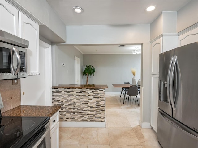 kitchen with white cabinets, appliances with stainless steel finishes, decorative backsplash, and dark stone counters