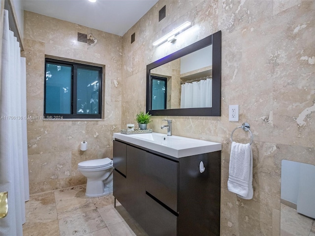 bathroom with vanity, toilet, and tile walls