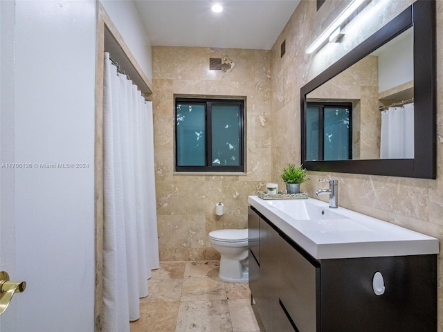 bathroom with vanity, toilet, and tile walls