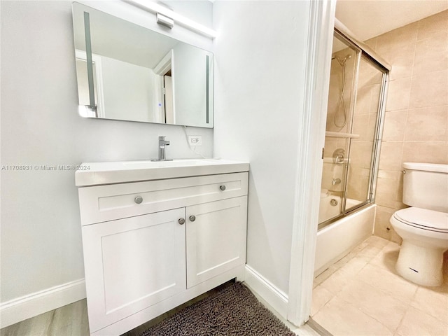 full bathroom featuring shower / bath combination with glass door, tile patterned flooring, vanity, and toilet