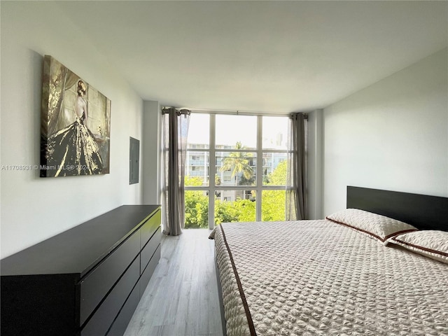 bedroom featuring electric panel, light hardwood / wood-style flooring, and floor to ceiling windows