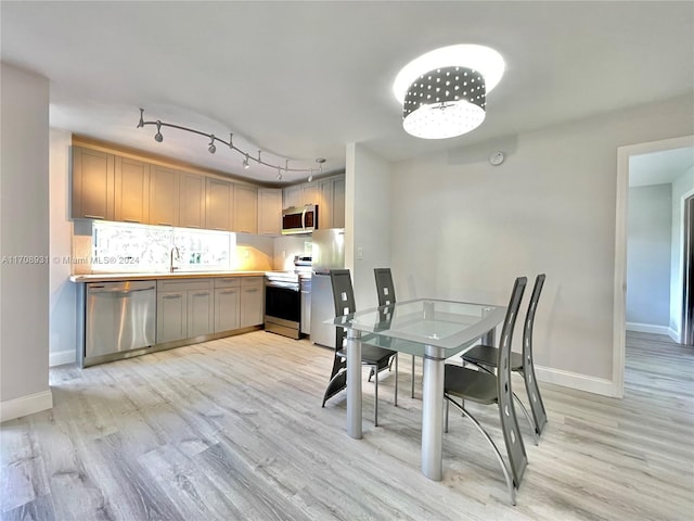 dining area featuring sink, rail lighting, and light hardwood / wood-style flooring