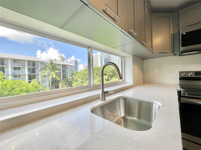 kitchen featuring light stone counters, sink, and stainless steel appliances