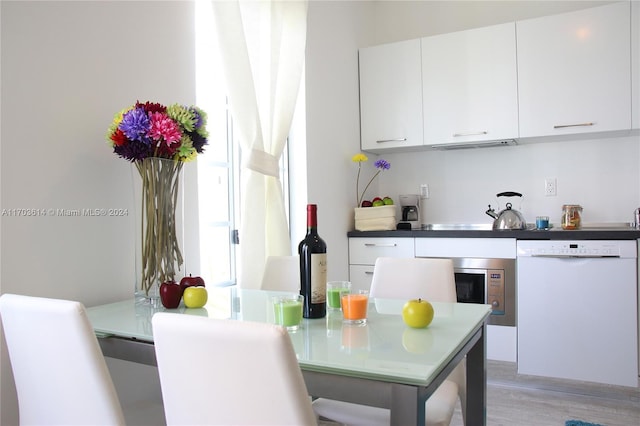 kitchen featuring white dishwasher, white cabinetry, and light hardwood / wood-style flooring