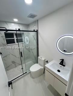 bathroom featuring vanity, toilet, and a shower with shower door