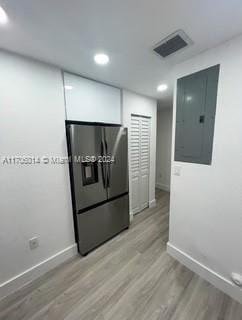 kitchen featuring electric panel, light hardwood / wood-style floors, and stainless steel refrigerator with ice dispenser