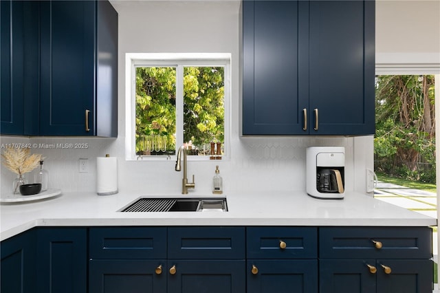 kitchen with plenty of natural light, sink, blue cabinetry, and decorative backsplash