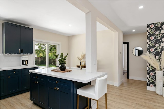 kitchen featuring a breakfast bar, tasteful backsplash, a center island, blue cabinetry, and light hardwood / wood-style flooring