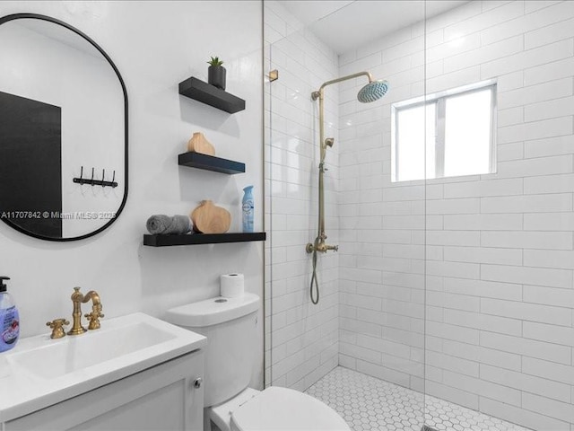 bathroom featuring vanity, toilet, and a tile shower