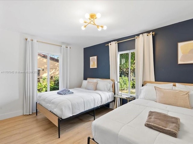 bedroom with light hardwood / wood-style floors and a notable chandelier