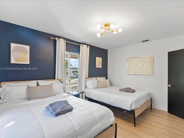 bedroom with hardwood / wood-style floors and an inviting chandelier