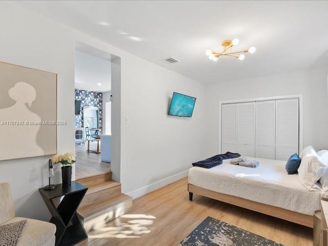 bedroom with an inviting chandelier, a closet, and light wood-type flooring