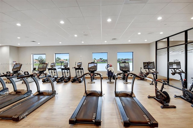 gym with a paneled ceiling and light wood-type flooring