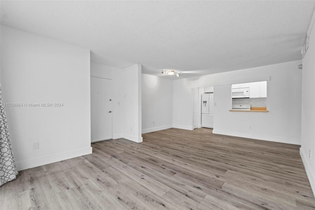 unfurnished living room with a textured ceiling and light hardwood / wood-style floors