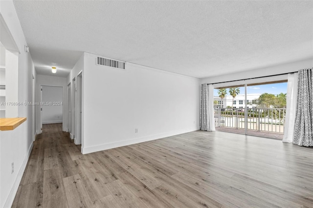 empty room featuring light wood-type flooring and a textured ceiling