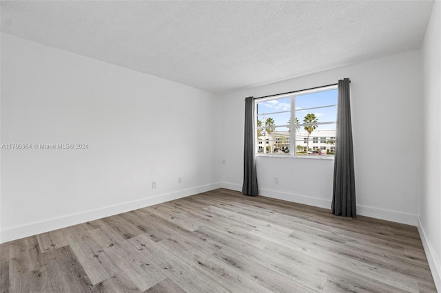 empty room with light hardwood / wood-style flooring and a textured ceiling