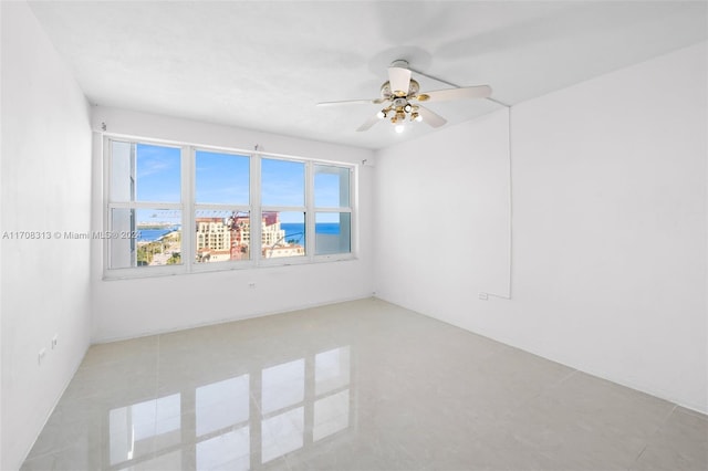 empty room with ceiling fan and light tile patterned flooring