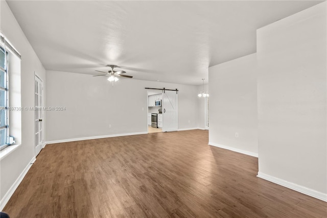 unfurnished living room featuring a barn door, plenty of natural light, and dark hardwood / wood-style floors