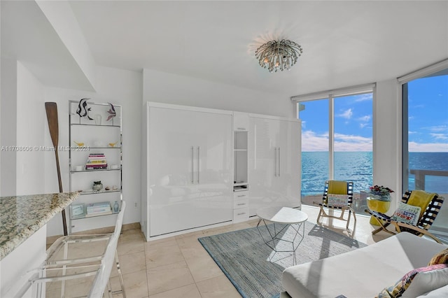 tiled living room with a water view and expansive windows