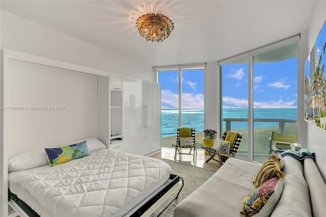 bedroom featuring a water view, wood-type flooring, and a wall of windows