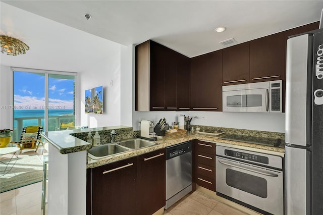 kitchen with sink, stainless steel appliances, kitchen peninsula, dark stone counters, and a water view