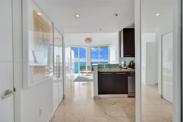 kitchen featuring light stone countertops, dark brown cabinets, a water view, and stainless steel dishwasher