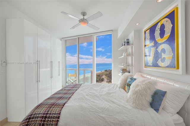 bedroom featuring ceiling fan, a water view, access to outside, and multiple windows