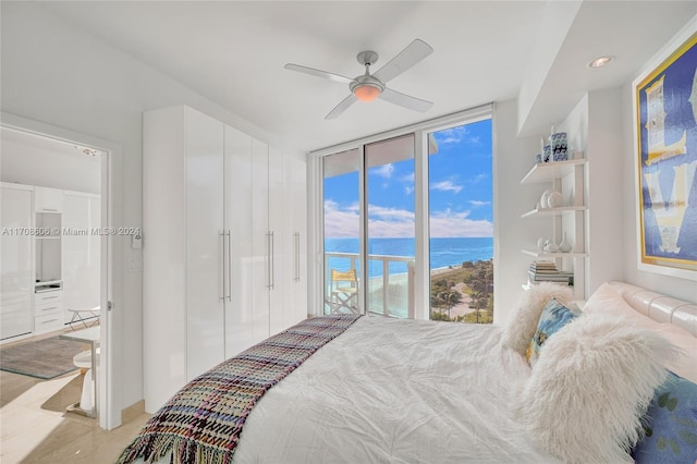 bedroom with ceiling fan, a water view, access to outside, and multiple windows