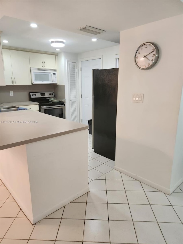 kitchen featuring white cabinets, black fridge, electric range, light tile patterned flooring, and kitchen peninsula