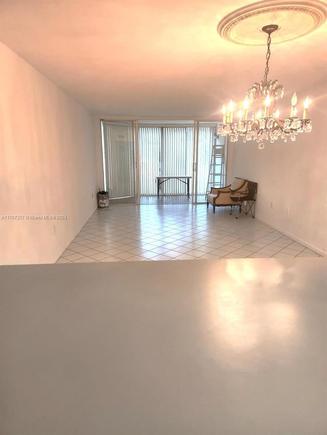 tiled spare room featuring an inviting chandelier