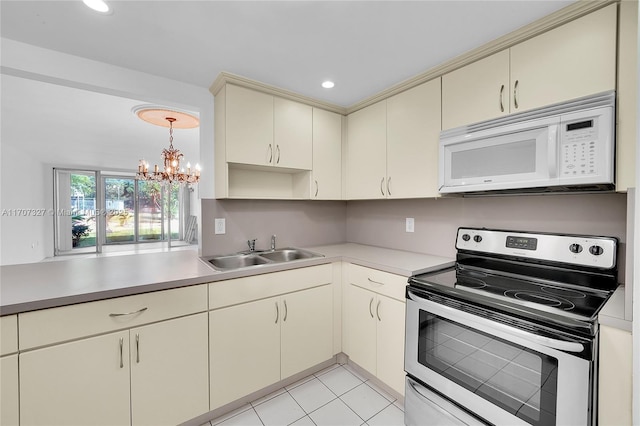 kitchen with an inviting chandelier, cream cabinetry, stainless steel electric range oven, a sink, and white microwave