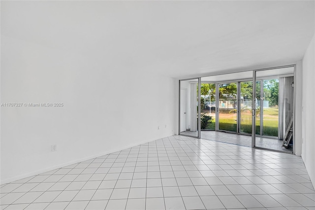 empty room featuring a wall of windows and light tile patterned floors