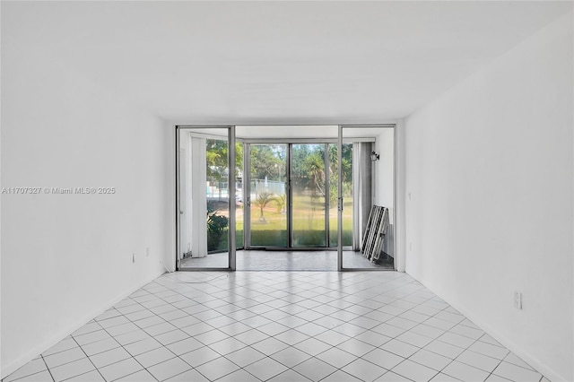 unfurnished room with light tile patterned floors and a wall of windows