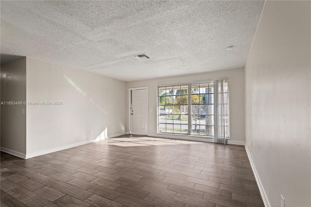 unfurnished room featuring dark hardwood / wood-style flooring and a textured ceiling