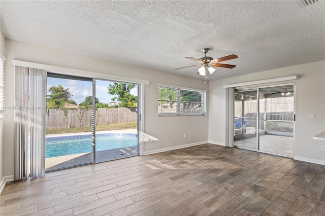 empty room with a textured ceiling, hardwood / wood-style flooring, and ceiling fan