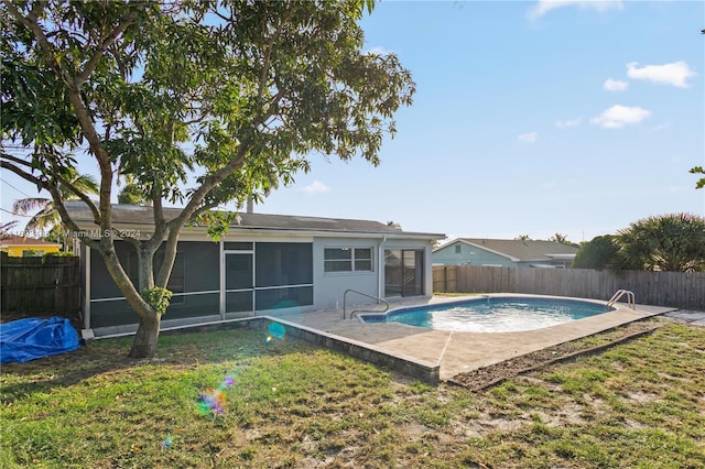 view of swimming pool featuring a lawn, a patio area, and a sunroom