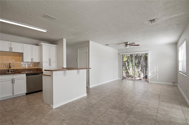 kitchen featuring stainless steel dishwasher, ceiling fan, white cabinetry, and a textured ceiling